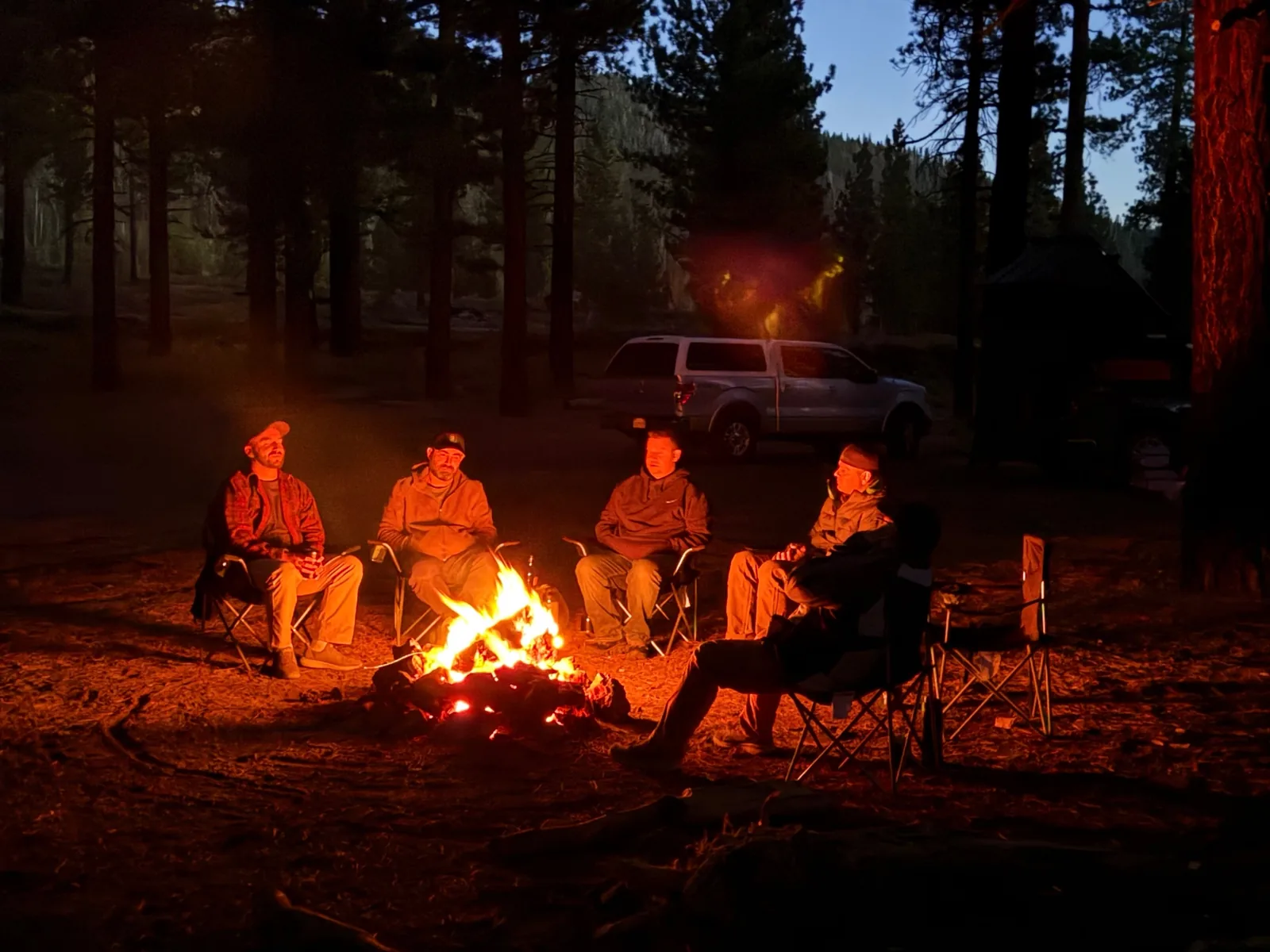 Men gathered around a campfire in the Sierra forest